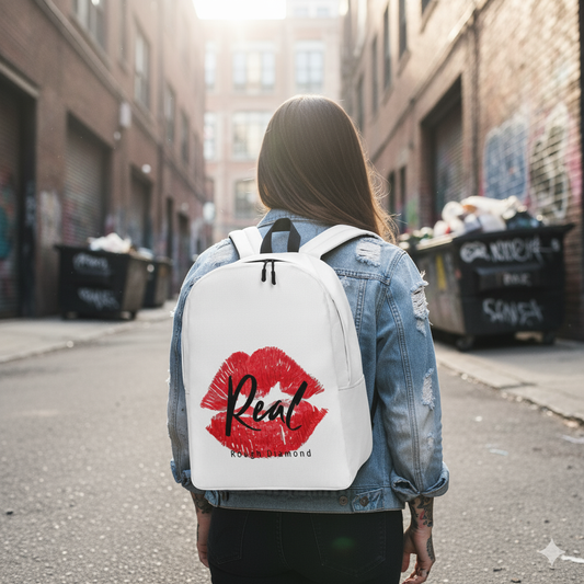 Person wearing a white backpack with red lipstick design and 'Real' text on a city street.